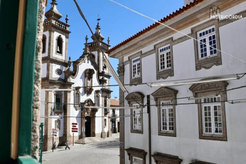Vista da icónica praça de Guarda com fachada de igreja em pedra branca e arquitetura portuguesa tradicional, SM Stays