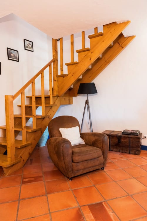 Escada de madeira com poltrona de couro marrom na sala de estar da villa Casas de Juromenha, pisos de terracota, decoração rústica