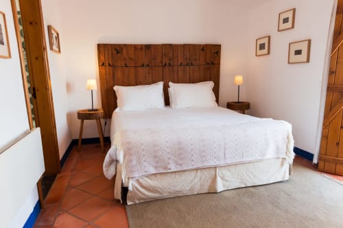 Quarto espaçoso na vila Casas de Juromenha em Portugal com cabeceira de madeira, roupas de cama brancas e piso de azulejos de terracota