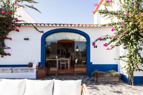 Vila caiada com porta em arco azul cercada por buganvílias magenta em Casas de Juromenha, Portugal