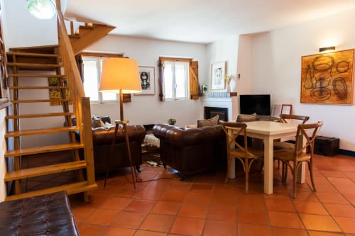 Área de estar integrada na villa Casa 5 em Juromenha com escada de madeira, sofá de couro marrom, mesa de jantar e lareira