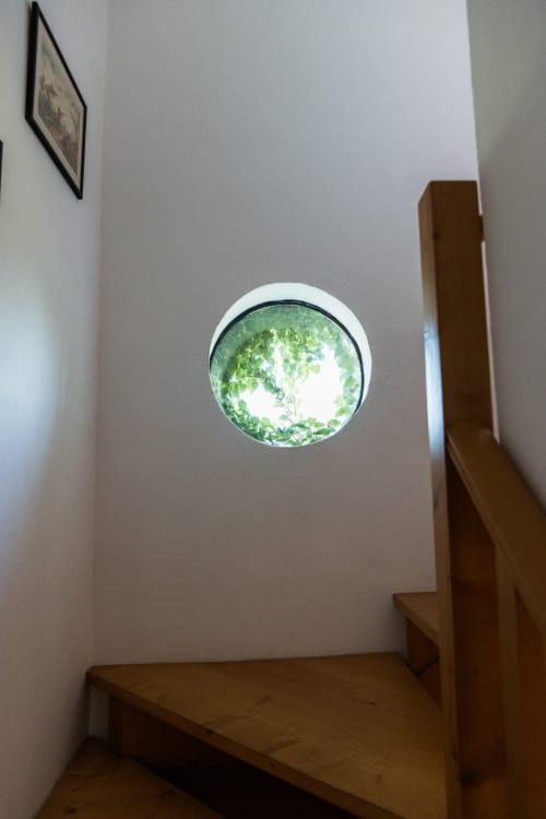 Janela circular com vista de folhagem verde na escadaria da villa Casas de Juromenha, Portugal
