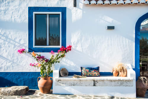 Exterior da villa mediterrânea em azul brilhante e branco em Casas de Juromenha com plantas floridas e confortáveis áreas de estar