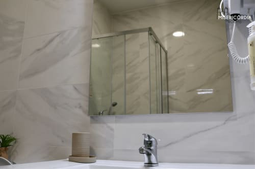 Casa de banho moderna na SM Stays Collection em Guarda com azulejos de mármore, armário espelhado e torneira cromada