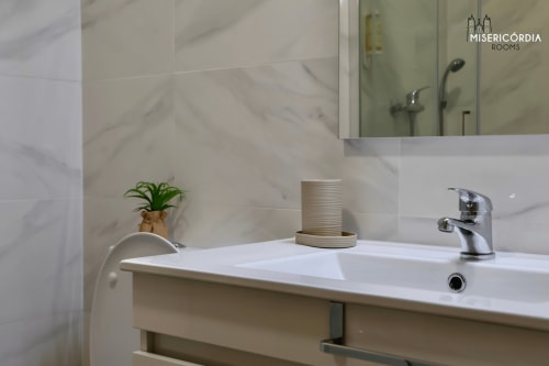 Banheiro moderno com paredes revestidas em mármore, torneira cromada e planta no hotel SM Stays Collection em Guarda, Portugal