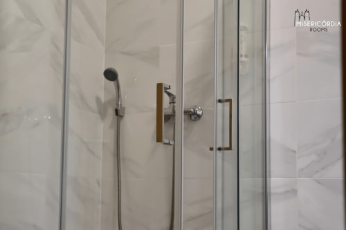 Moderno chuveiro de vidro com chuveiro de chuva e acabamento em bronze no hotel SM Stays Collection em Guarda, Portugal