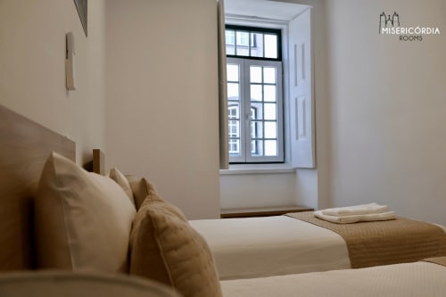 Quarto moderno da SM Stays Collection em Guarda com camas geminadas, roupa de cama creme e janela com vista para a cidade