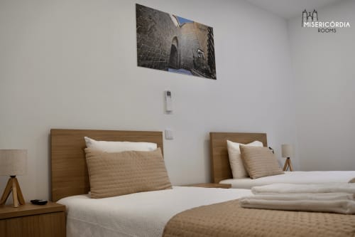 Quarto twin moderno no hotel Torre dos Ferreiros, Guarda com camas de madeira, roupas de cama neutras e arte com vista da cidade