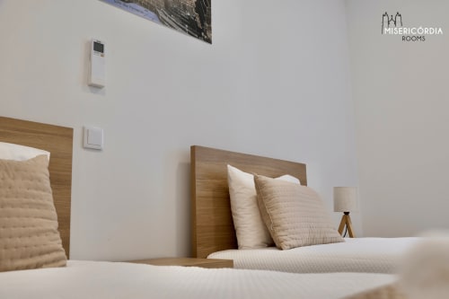 Quarto moderno da SM Stays Collection em Guarda com cabeceira em madeira, almofadas creme e decoração minimalista