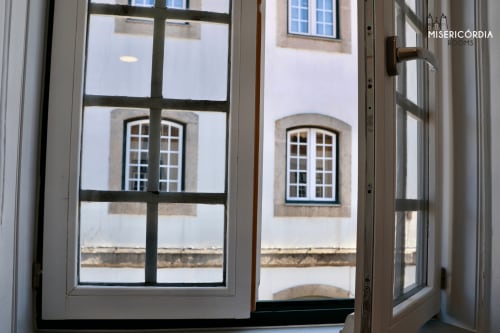 Vista da janela do quarto Torre dos Ferreiros em Guarda com fachada histórica de edifício com janelas em arco