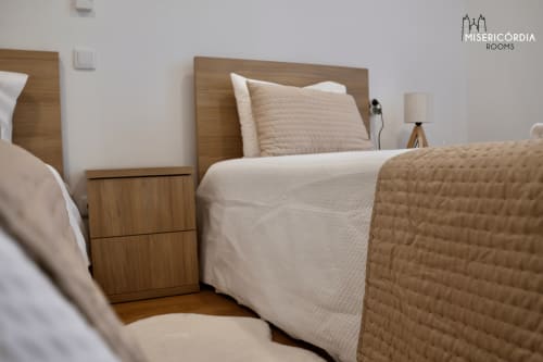 Quarto moderno da SM Stays Collection em Guarda com cabeceira em madeira, roupas de cama brancas, edredom acolchoado bege e acabamentos em madeira