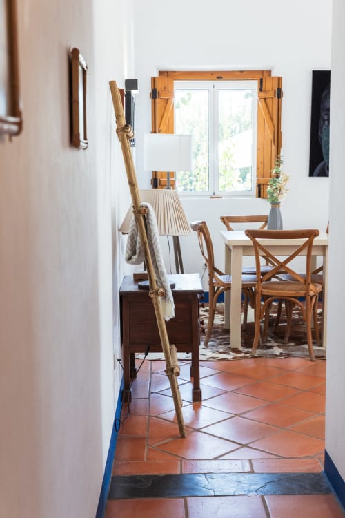 Sala de jantar clara com cadeiras de madeira, ladrilhos de terracota, assentos estilo escada e janelas com cortinas douradas na Casa 6