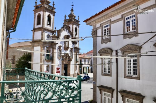 Igreja histórica com torres sineiras gémeas em Guarda, Portugal, vista da varanda de ferro verde do quarto do hotel SM Stays Collection