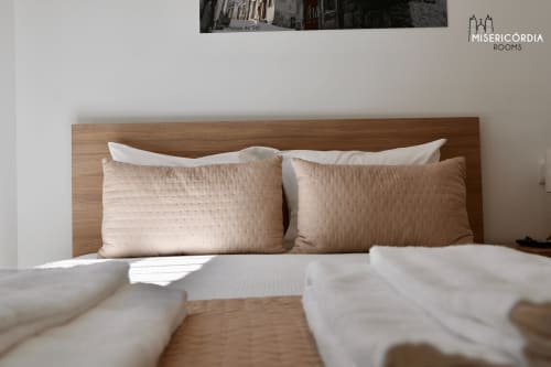 Cama com almofadas acolchoadas bege e roupas brancas no quarto Torre de Menagem da SM Stays Collection, Guarda Portugal