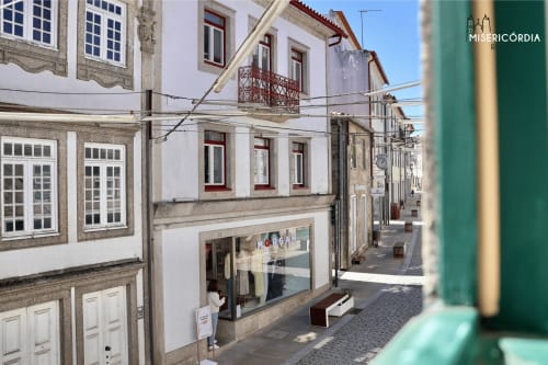 Rua de calçada histórica em Guarda, Portugal com edifícios brancos tradicionais e fachadas de pedra perto do SM Stays