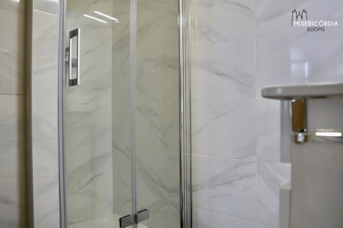 Moderno chuveiro em mármore na suíte Torre de Menagem do hotel SM Stays Collection em Guarda, Portugal
