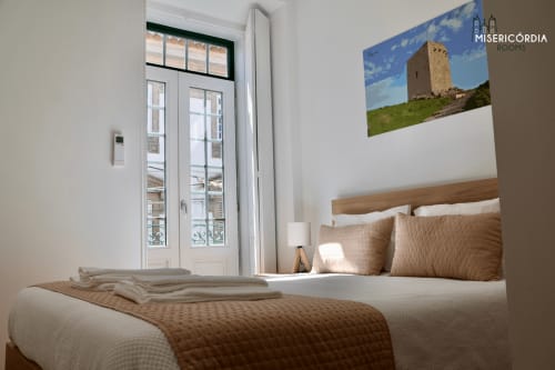 Quarto brilhante com cama de madeira, roupas de cama bege e portas para varanda com vista para Guarda na Torre de Menagem, SM Stays