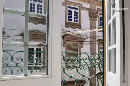 Varanda com gradil de ferro forjado verde com vista para o edifício histórico de Guarda, janelas com postigos azuis, sala Torre de Menagem
