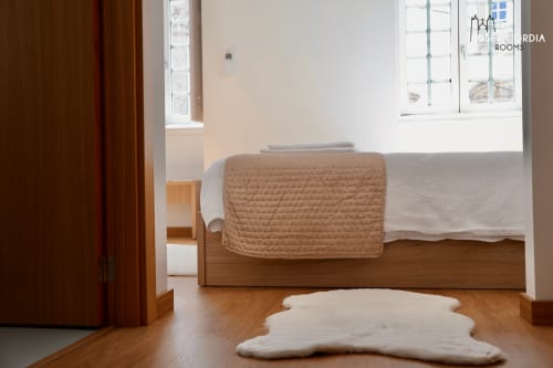 Quarto Sé Catedral na SM Stays Collection em Guarda com cama em madeira, manta bege e tapete de lã de ovelha branco