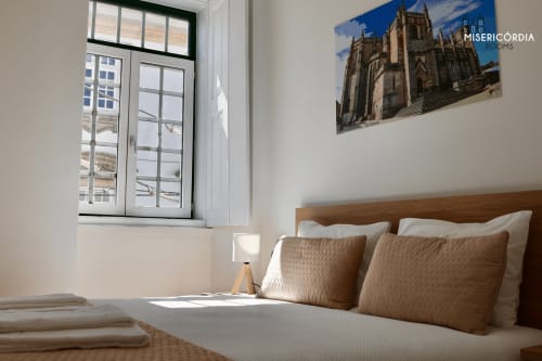 Quarto luminoso na Sé Catedral em Guarda com cama de madeira, vista da cidade pelas grandes janelas e obra de arte da catedral na parede
