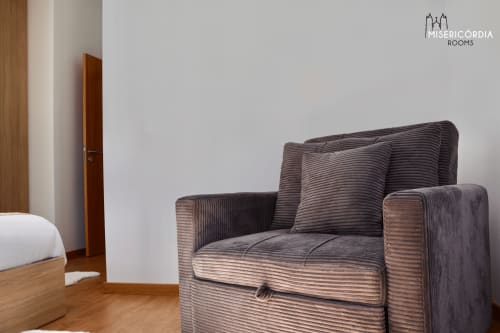 Quarto moderno na Coleção SM Stays em Guarda com poltrona estofada cinzenta e móveis de madeira