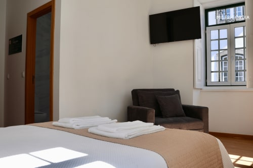 Quarto Sé Catedral na SM Stays Collection em Guarda, Portugal com cama, poltrona escura, TV de parede e vista para a cidade