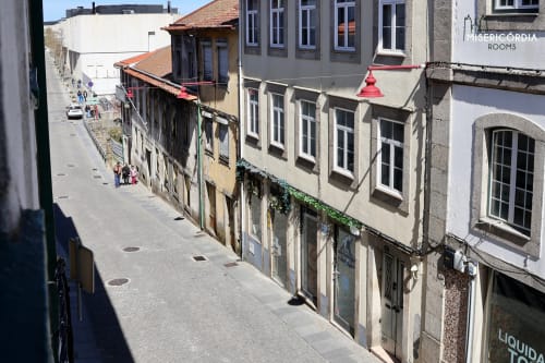 Rua de paralelepípedos histórica com edifícios tradicionais portugueses em Guarda. Hotel SM Stays Collection à direita.