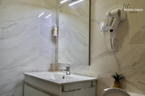 Casa de banho moderna da SM Stays Collection em Guarda com azulejos em mármore, lavatório, espelho, secador de cabelo e sanita