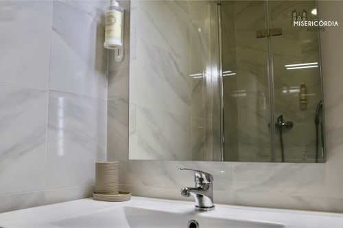 Banheiro moderno da suite Alameda em SM Stays Collection, Guarda, com azulejos de mármore, espelho e lavatório