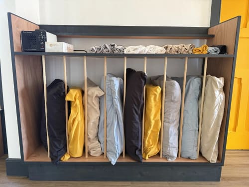Organized linen storage unit at Golden Mermaid Villa with rolled towels and linens in neutral and yellow tones
