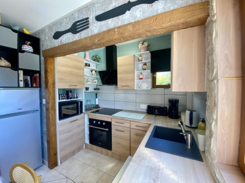 Cuisine moderne avec meubles en bois, électroménagers noirs et rangements ouverts du gîte Sarlat la Canéda.