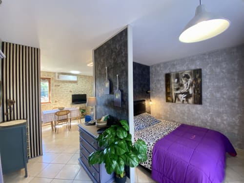 Chambre moderne Ô Clair De Lune à Sarlat : literie violette, murs texturés, luminaires suspendus, espace ouvert