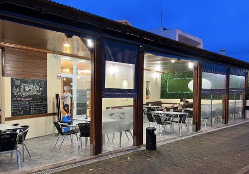 Golden Mermaid Villa's outdoor terrace at dusk with modern seating, illuminated storefront, and coastal Portuguese setting