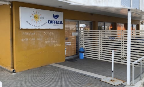O Sole Mio Caffecel Italian pizza restaurant entrance with yellow wall and striped gate at Golden Mermaid Villa, Portugal