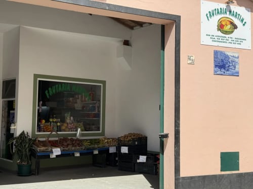 Frutaria Martins fruit market storefront with fresh produce display and green door entrance