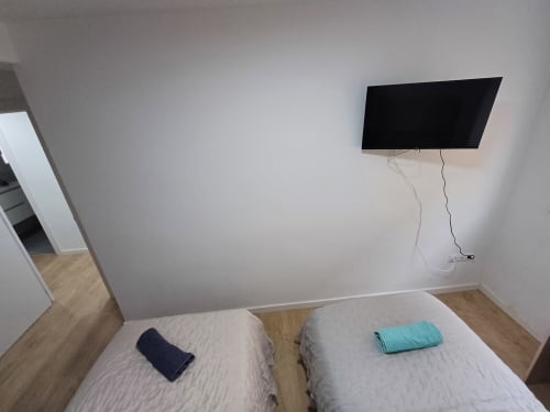 Modern bedroom in Algemesi Home apartment with two beds, wall-mounted flat-screen TV, and wooden flooring
