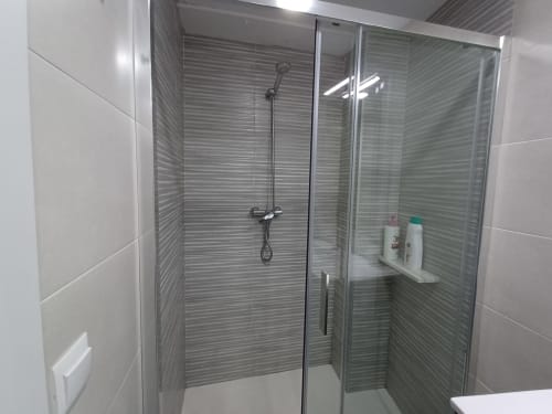 Modern shower enclosure with glass doors and gray tile walls at Algemesi Home apartment in Algemesi, Spain