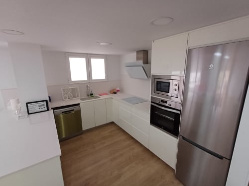 Modern kitchen in CARBO HOME apartment, Algemesi with white cabinetry, stainless steel appliances, and wooden flooring.