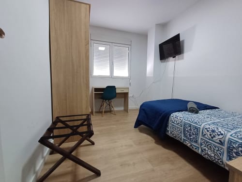 Modern bedroom at Algemesi Home apartment with bed, desk, TV, and wooden wardrobe in Algemesi, Spain