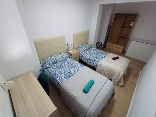 Dormitorio doble en el apartamento Algemesi Home con cabeceras crema, ropa de cama estampada, armario de madera y vistas a la ciudad