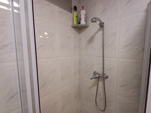 Salle de bain moderne de l'appartement Algemesi Home avec carrelage marbre, pommeau de douche mural et étagère d'accessoires