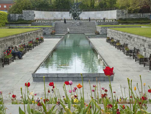 Memorial garden with reflecting pool, red tulips, and stone monument in Dublin