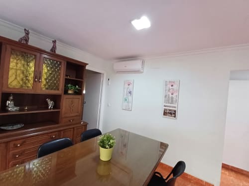 Salle à manger de l'appartement Algemesi Home avec mobilier bois, table à manger, plante en pot et vue sur la ville