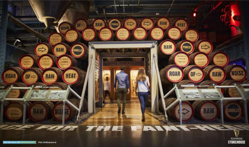 Guinness Storehouse Dublin entrance with barrel displays and visitors walking through archway