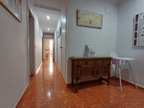 Couloir de l'appartement Algemesi Home avec mobilier en bois, chaises blanches, carrelage en terre cuite et équipements modernes