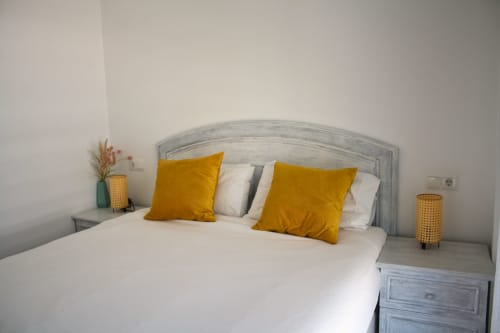 Dormitorio moderno con cabecero gris, ropa de cama blanca y almohadas doradas en el apartamento Love Rent4 Málaga en Torremolinos