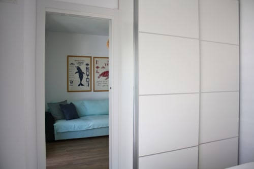 Pasillo de apartamento moderno con armario de cristal y vista al salón con sofá azul, hotel Torremolinos con vistas al mar