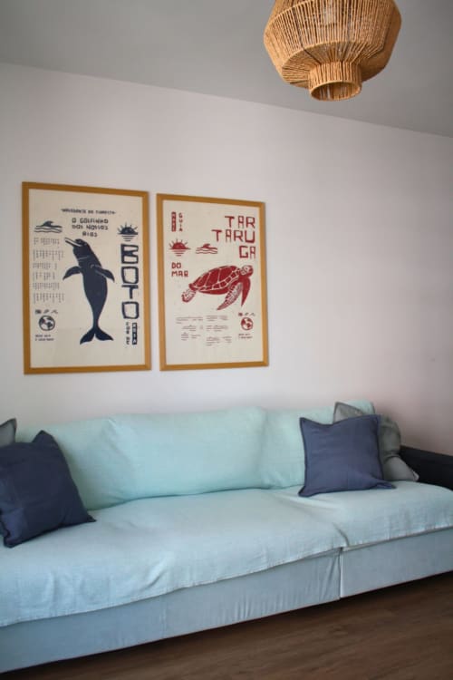 Apartamento moderno en Torremolinos con sofá azul claro, arte mural náutico con delfín y tortuga marina, y lámpara colgante trenzada