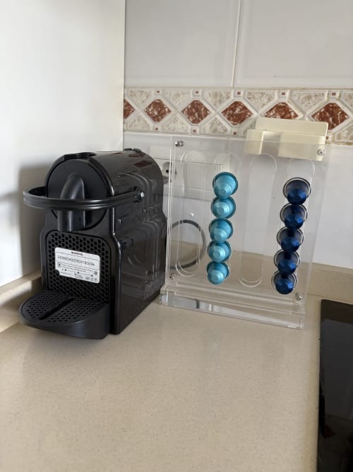Cafetera Nespresso negra con almacenamiento de cápsulas acrílico transparente mostrando vainas de café azules en una cocina de apartamento en Málaga.