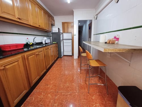 Cuisine moderne avec armoires en bois, carrelage rouge, coin repas avec bar à l'appartement Algemesi Home à Algemesi